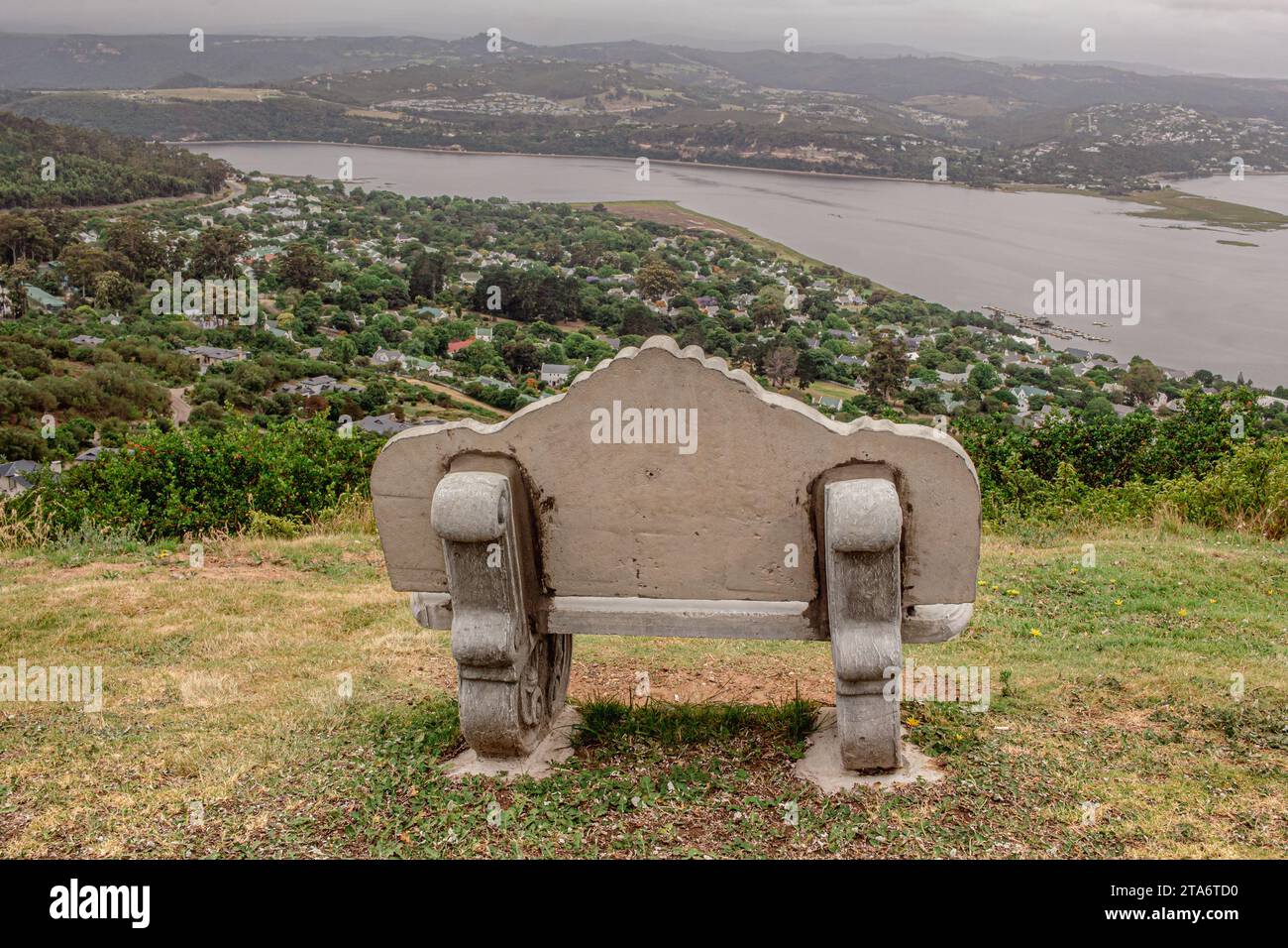 Panca solitaria in cemento con vista sul fiume vicino a Knysna, Sudafrica Foto Stock