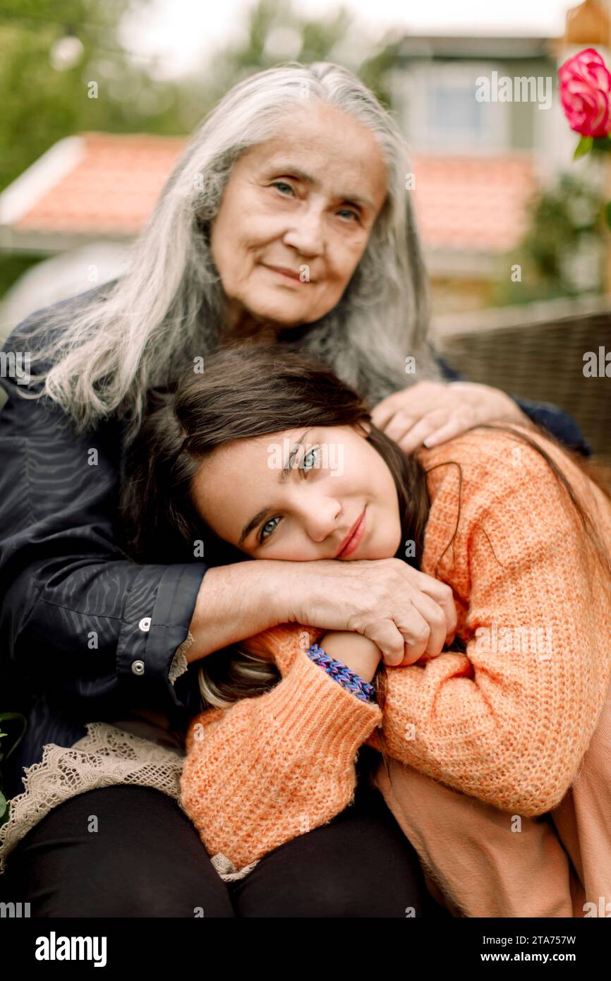 Ritratto di una nipote sorridente che tiene per mano e abbraccia la nonna Foto Stock