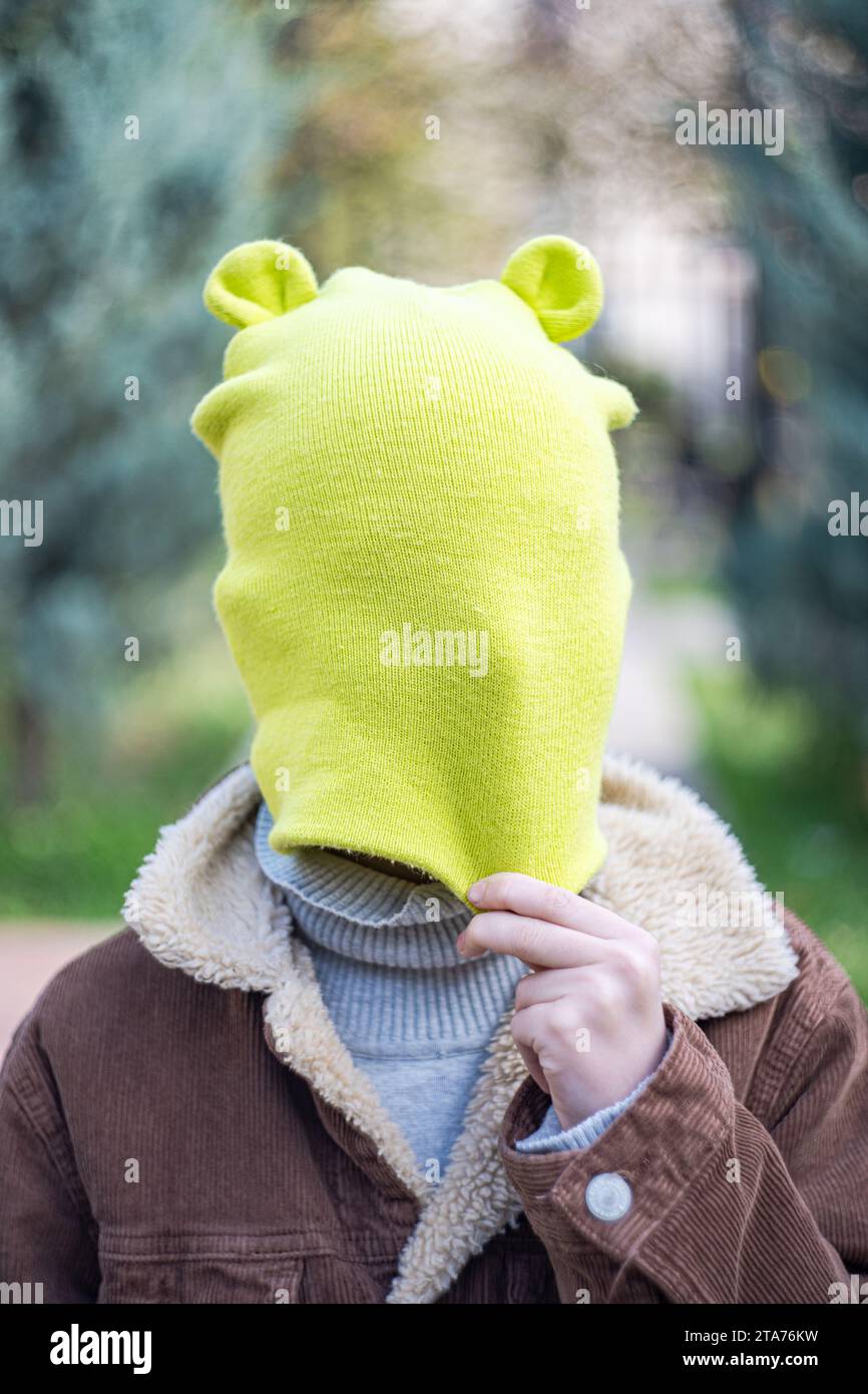 Ritratto ravvicinato di un ragazzo in piedi in un parco che gli tira un cappello con le orecchie in faccia, Georgia Foto Stock