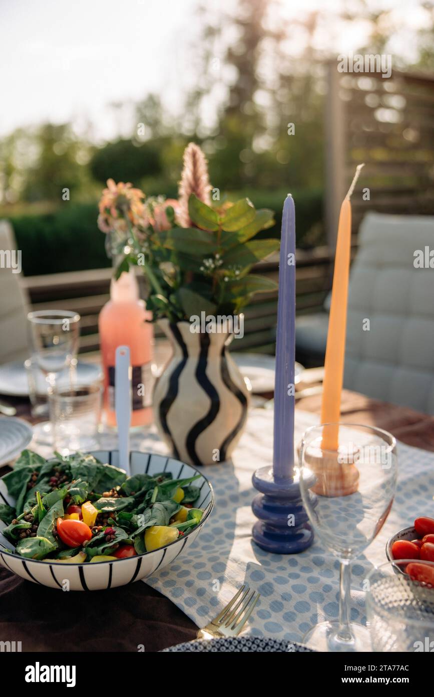 Le candele sono tenute vicino alla ciotola per insalate sul tavolo durante la festa nel cortile sul retro Foto Stock