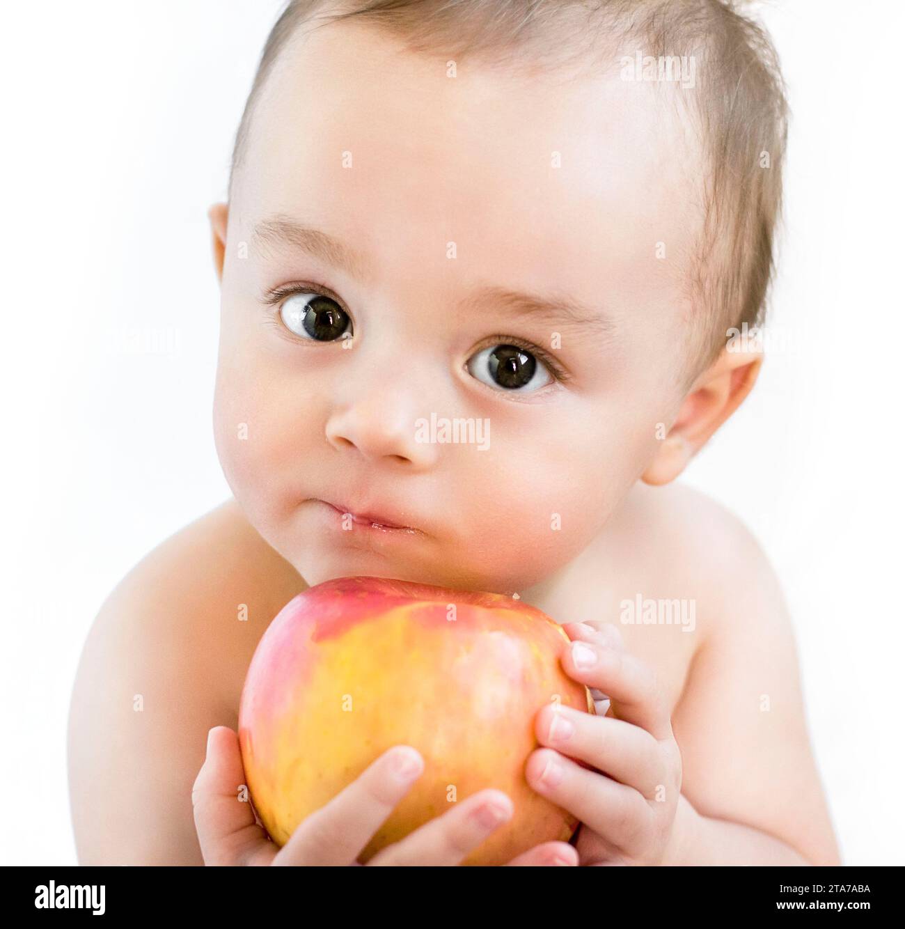 Un bambino curioso dagli occhi luminosi che regge una nuova mela: Un ritratto di innocenza ed esplorazione Foto Stock