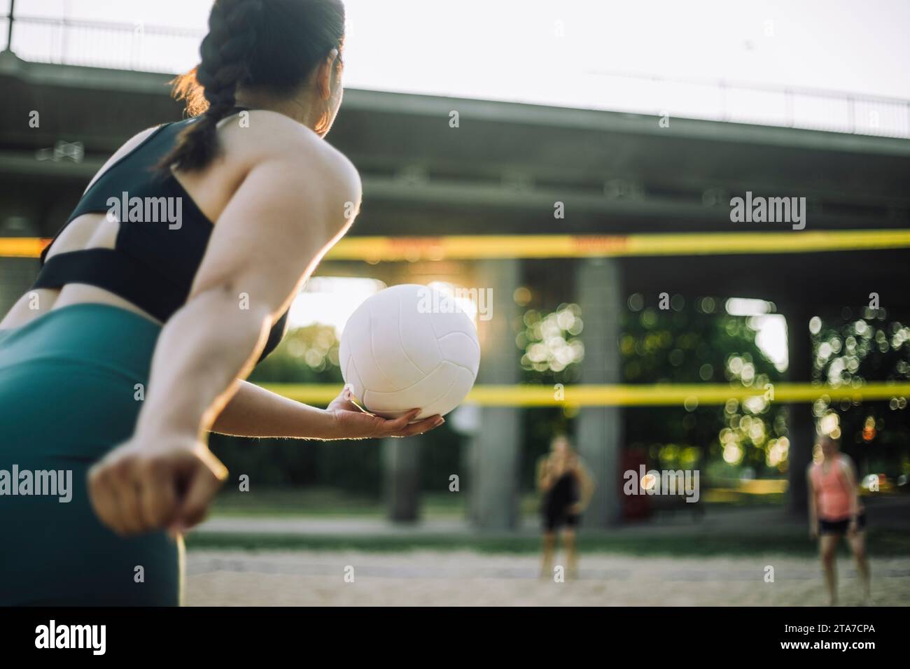 Donna che si prepara al servizio mentre gioca a pallavolo con gli amici Foto Stock