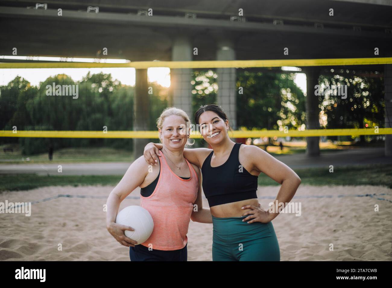 Ritratto di una donna sorridente con un braccio intorno a un'amica che tiene un pallavolo Foto Stock