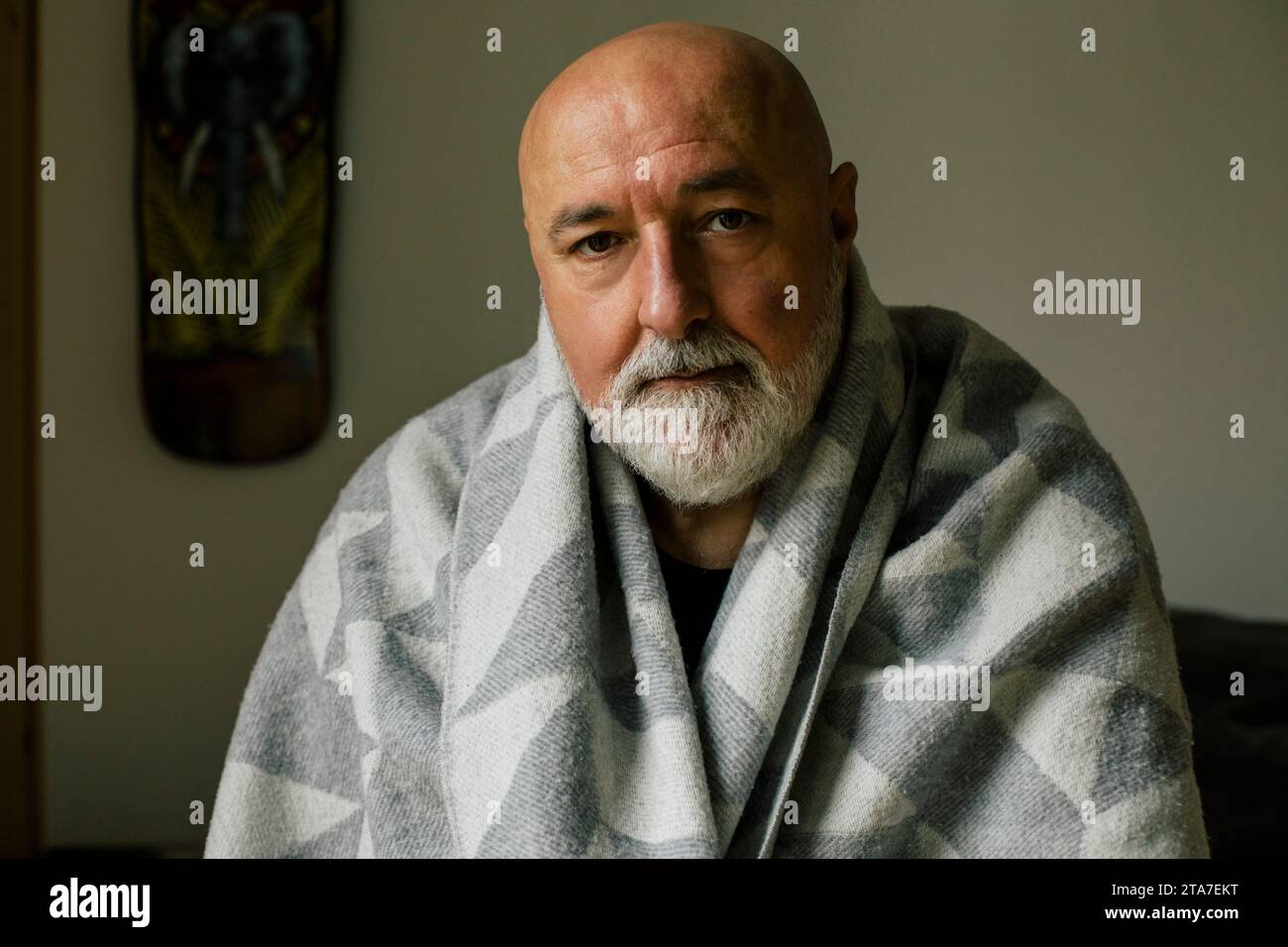 Ritratto di un uomo serio maturo avvolto in una coperta a casa Foto Stock