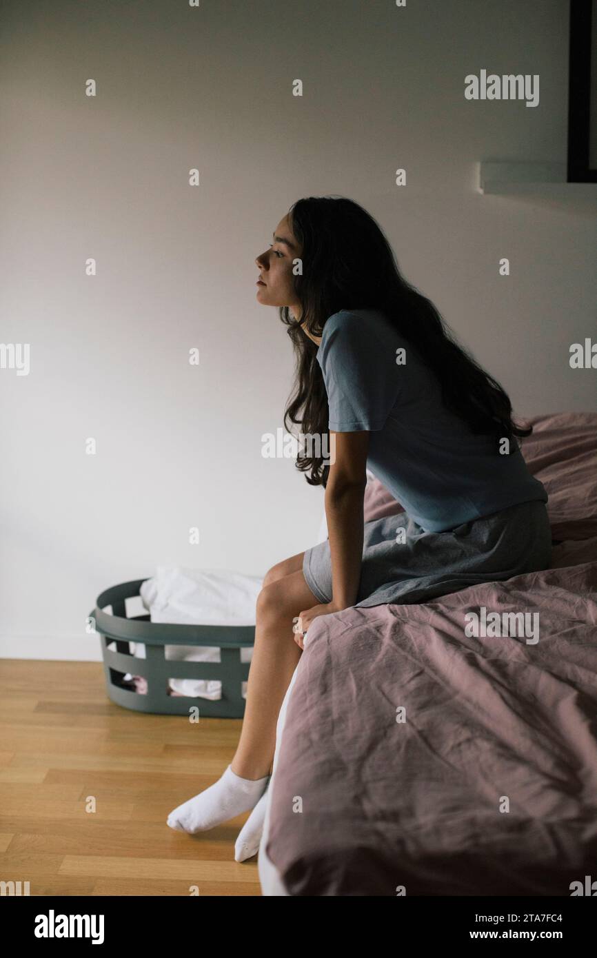 Donna depressa seduta sul letto a casa Foto Stock