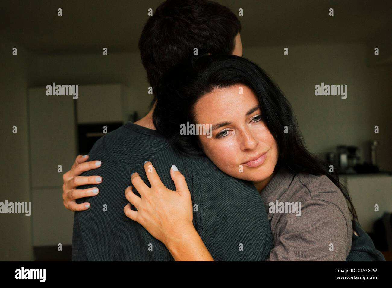 Donna premurosa che abbraccia il figlio a casa Foto Stock