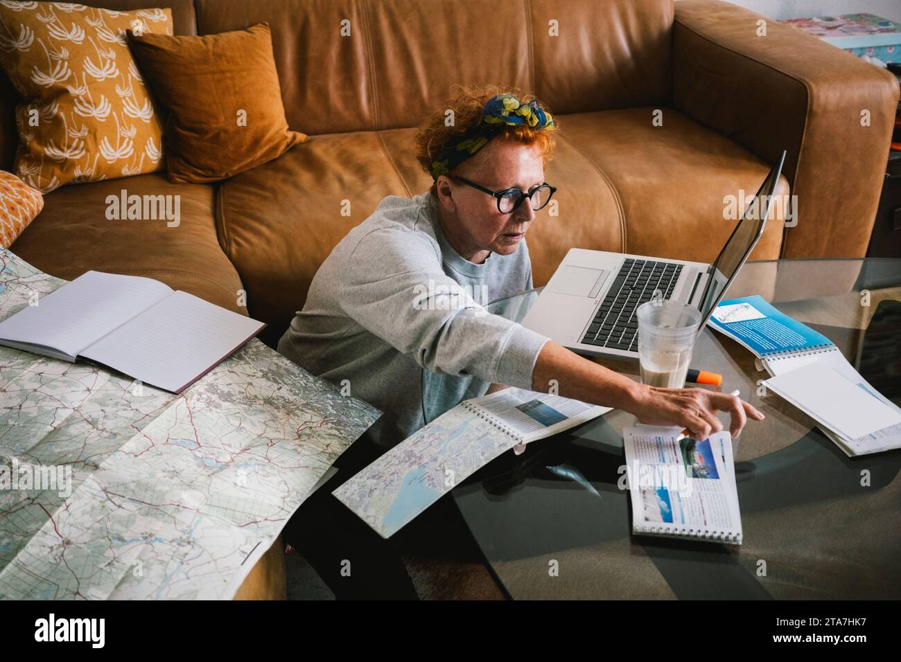 Donna anziana con mappa e documenti che pianificano il viaggio a casa Foto Stock