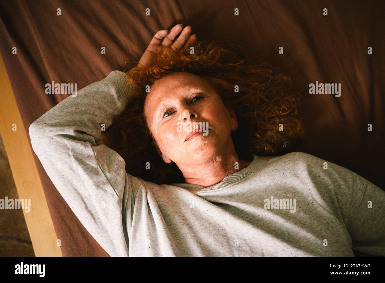 Vista dall'alto di una donna anziana premurosa sdraiata sul letto a casa Foto Stock