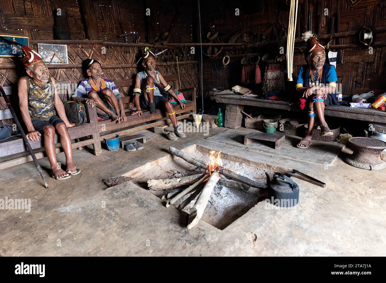 Anziani, uomini, guerrieri di una tribù konyak con tatuaggi tribali sui volti e cappelli tradizionali, collane, orecchini, seduti in casa, Nagaland, India Foto Stock