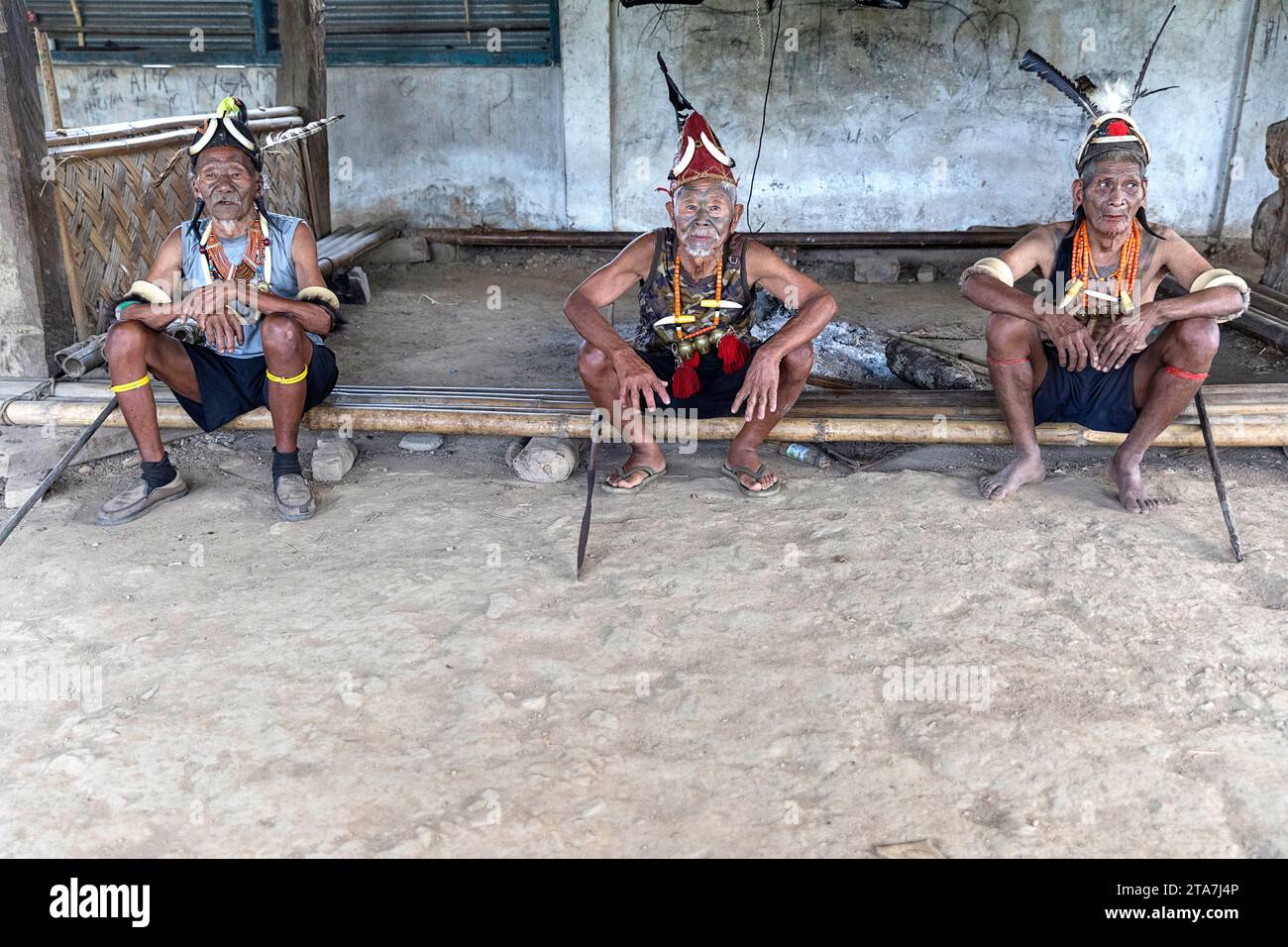 Anziani della tribù Konyak, guerrieri con splendidi ornamenti tribali e tatuaggi facciali, Nagaland, India, anziani seduti in una casa sacra Foto Stock