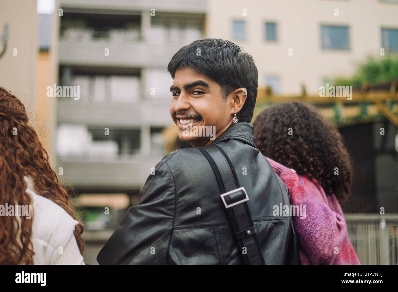 Ritratto di un ragazzo sorridente che guarda a spalla con le amiche Foto Stock