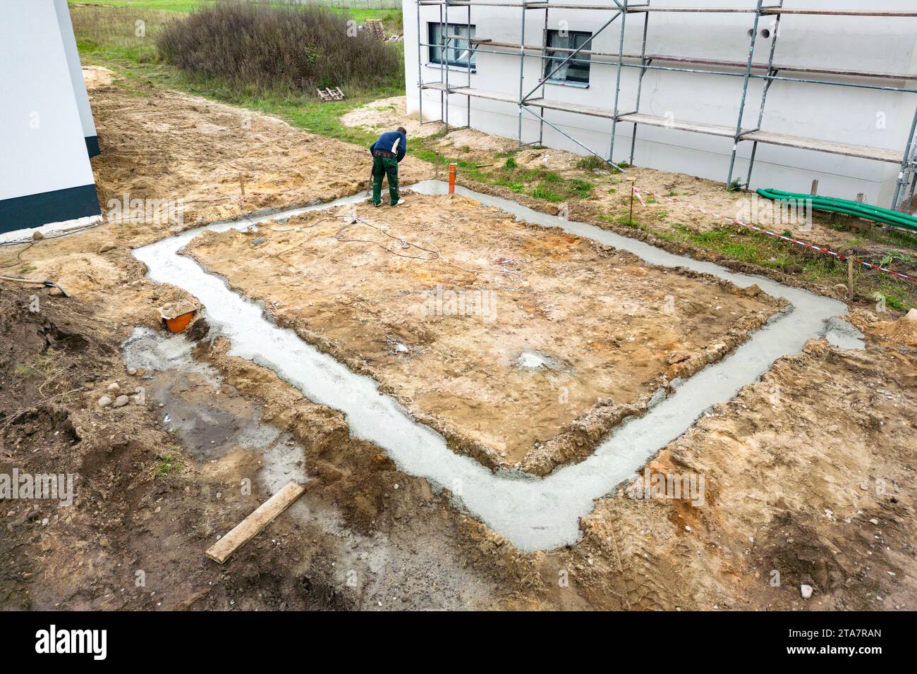 Fondamenta di cemento appena versate accanto a un'unica casa di famiglia Foto Stock