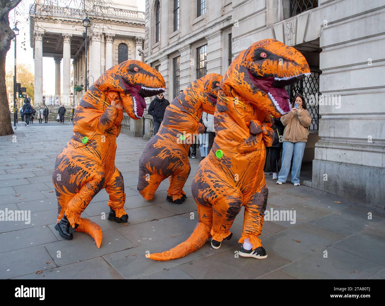Londra, Regno Unito. 28 novembre 2023. I Dancing Dinasours si esibivano oggi a Londra da Trafalgar Square. Potrebbero essere stati ballerini del musical del West End The Lion King. I manifestanti anti anti Ultra Low Emission zone sono stati visti anche a Londra in alcune occasioni, vestiti da dinasours che bloccano i furgoni fotografici ULEZ mobili che scattano immagini di auto nelle aree ULEZ. Credito: Maureen McLean/Alamy Live News Foto Stock
