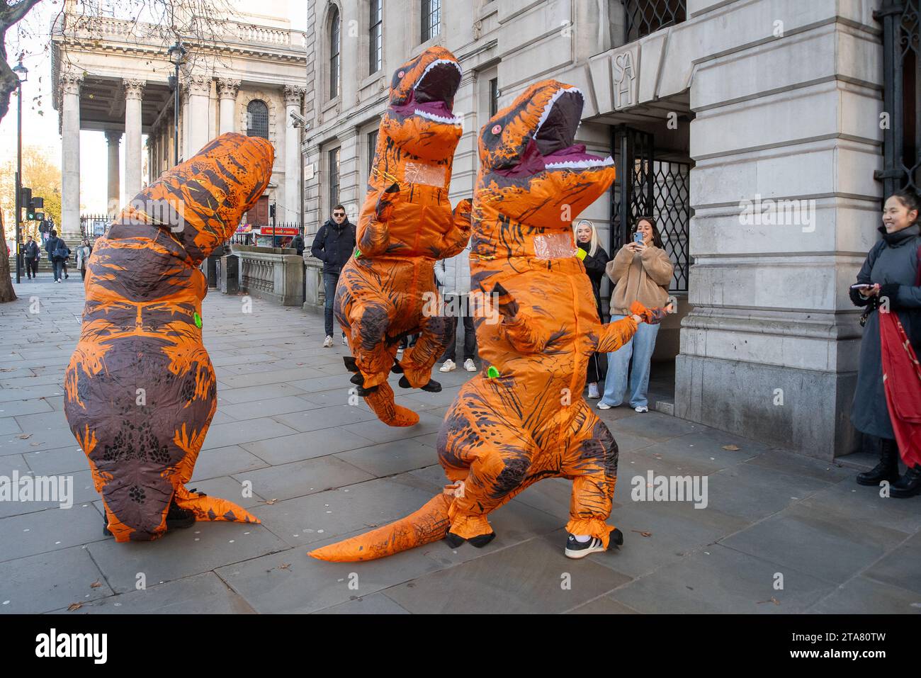 Londra, Regno Unito. 28 novembre 2023. I Dancing Dinasours si esibivano oggi a Londra da Trafalgar Square. Potrebbero essere stati ballerini del musical del West End The Lion King. I manifestanti anti anti Ultra Low Emission zone sono stati visti anche a Londra in alcune occasioni, vestiti da dinasours che bloccano i furgoni fotografici ULEZ mobili che scattano immagini di auto nelle aree ULEZ. Credito: Maureen McLean/Alamy Live News Foto Stock