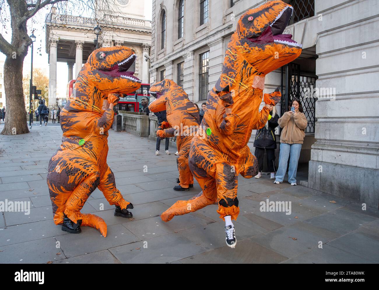 Londra, Regno Unito. 28 novembre 2023. I Dancing Dinasours si esibivano oggi a Londra da Trafalgar Square. Potrebbero essere stati ballerini del musical del West End The Lion King. I manifestanti anti anti Ultra Low Emission zone sono stati visti anche a Londra in alcune occasioni, vestiti da dinasours che bloccano i furgoni fotografici ULEZ mobili che scattano immagini di auto nelle aree ULEZ. Credito: Maureen McLean/Alamy Live News Foto Stock