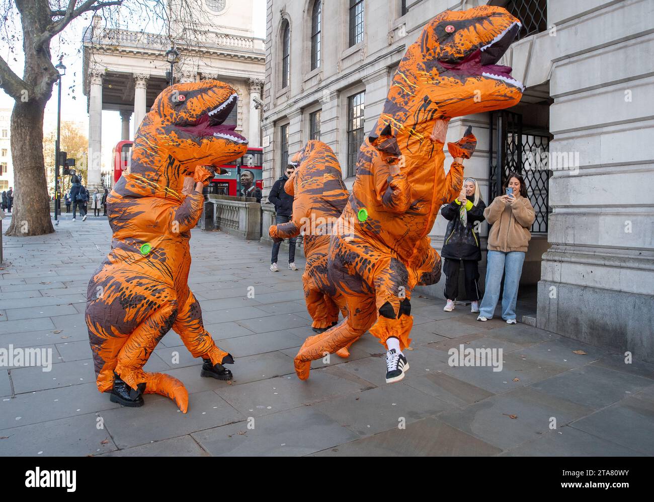 Londra, Regno Unito. 28 novembre 2023. I Dancing Dinasours si esibivano oggi a Londra da Trafalgar Square. Potrebbero essere stati ballerini del musical del West End The Lion King. I manifestanti anti anti Ultra Low Emission zone sono stati visti anche a Londra in alcune occasioni, vestiti da dinasours che bloccano i furgoni fotografici ULEZ mobili che scattano immagini di auto nelle aree ULEZ. Credito: Maureen McLean/Alamy Live News Foto Stock