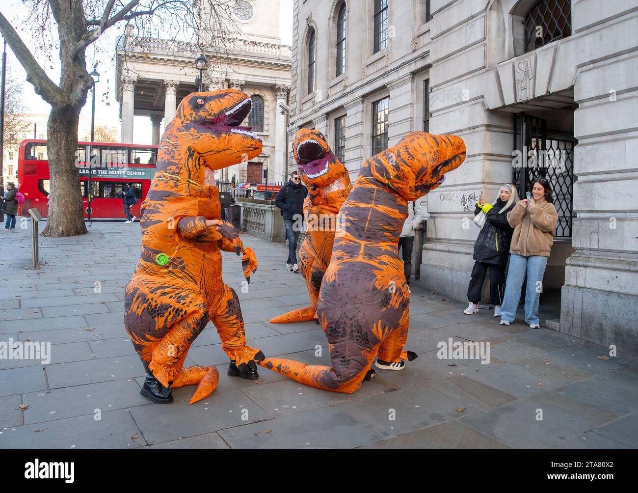 Londra, Regno Unito. 28 novembre 2023. I Dancing Dinasours si esibivano oggi a Londra da Trafalgar Square. Potrebbero essere stati ballerini del musical del West End The Lion King. I manifestanti anti anti Ultra Low Emission zone sono stati visti anche a Londra in alcune occasioni, vestiti da dinasours che bloccano i furgoni fotografici ULEZ mobili che scattano immagini di auto nelle aree ULEZ. Credito: Maureen McLean/Alamy Live News Foto Stock