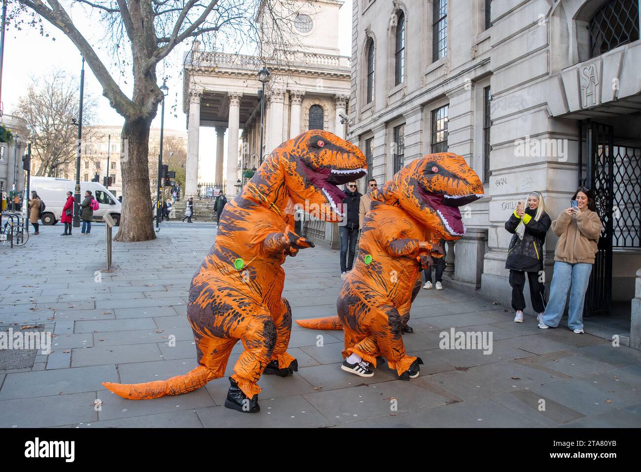 Londra, Regno Unito. 28 novembre 2023. I Dancing Dinasours si esibivano oggi a Londra da Trafalgar Square. Potrebbero essere stati ballerini del musical del West End The Lion King. I manifestanti anti anti Ultra Low Emission zone sono stati visti anche a Londra in alcune occasioni, vestiti da dinasours che bloccano i furgoni fotografici ULEZ mobili che scattano immagini di auto nelle aree ULEZ. Credito: Maureen McLean/Alamy Live News Foto Stock