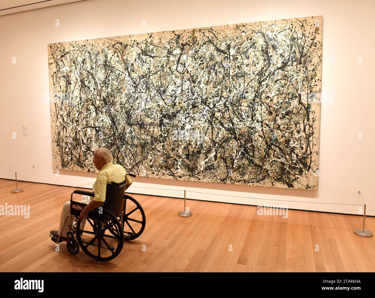 New York, USA - 25 maggio 2018: Un uomo in sedia a rotelle guarda il dipinto di Jackson Pollock al Museum of Modern Art di New York City. Foto Stock