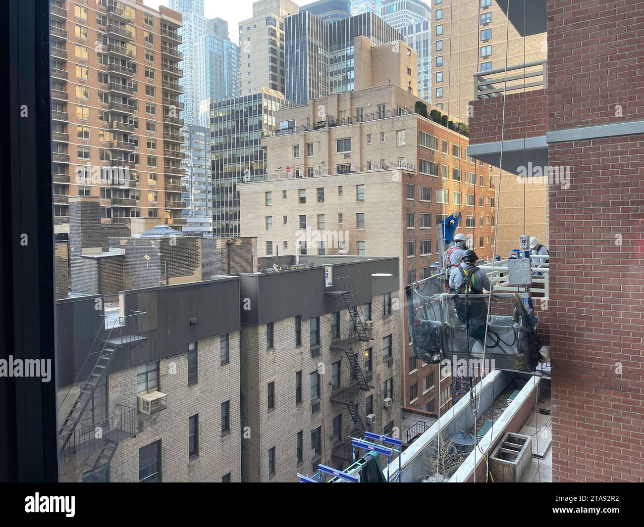 Uomini su una piattaforma sospesa che lavorano all'esterno di un edificio residenziale, 2023, New York City, USA Foto Stock Uomini su una piattaforma sospesa che lavorano all'esterno di un edificio residenziale, 2023, New York City, USA Foto Stock