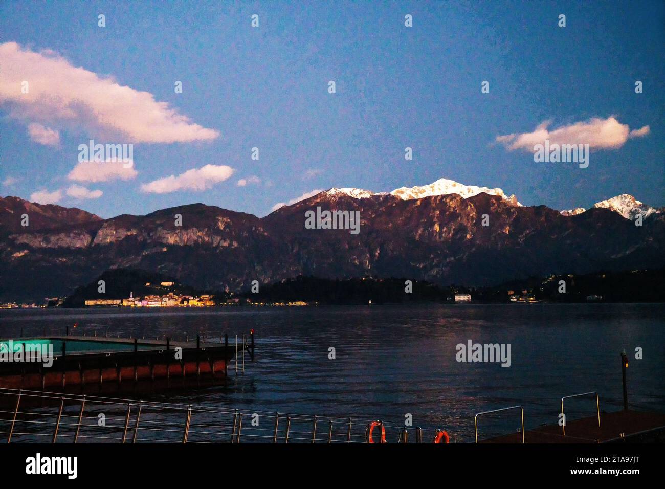 Stupita vista serale al tramonto sul lago di Como con le Alpi italiane (montagne innevate) e la città - Bellagio (?). Breve viaggio durante la settimana di Natale! Foto Stock