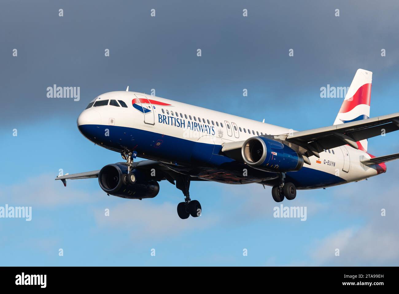 British Airways Airbus A320-232 aereo di linea G-EUYN in finale per atterrare all'aeroporto di Londra Heathrow, Regno Unito, in tarda inverno, al sole contro il cielo oscurante Foto Stock