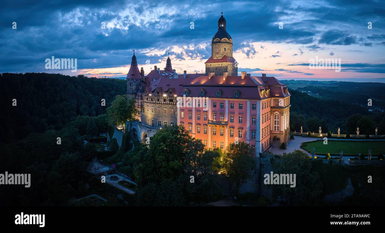 Vista aerea serale del castello illuminato di Ksiaz, Schloss Fürstenstein, un bellissimo castello che sorge su una roccia circondata dalla foresta nella bassa Slesia Foto Stock