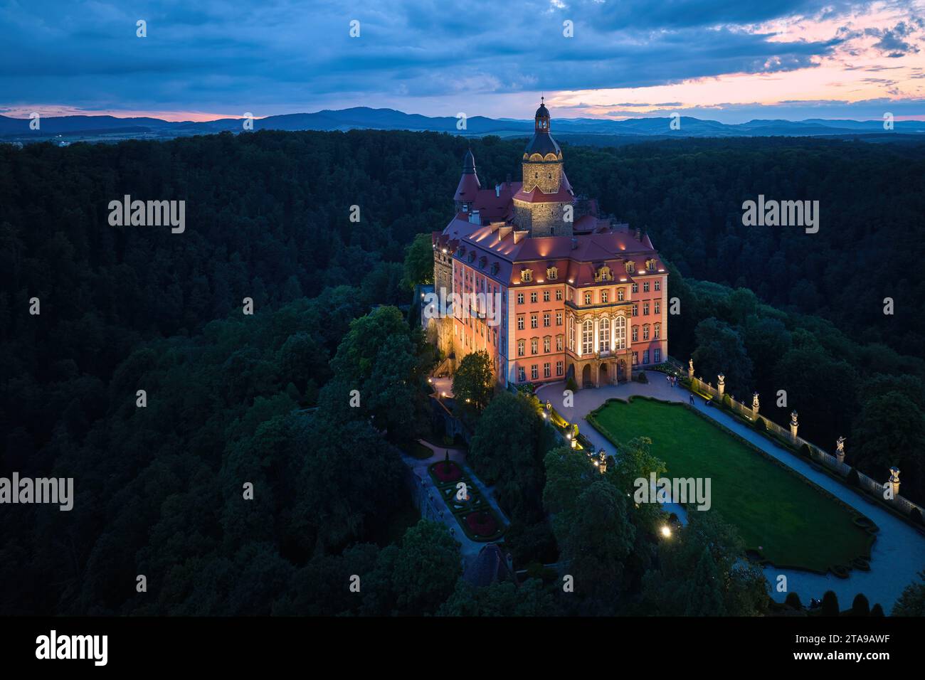 Vista aerea serale del castello illuminato di Ksiaz, Schloss Fürstenstein, un bellissimo castello che sorge su una roccia circondata dalla foresta nella bassa Slesia Foto Stock