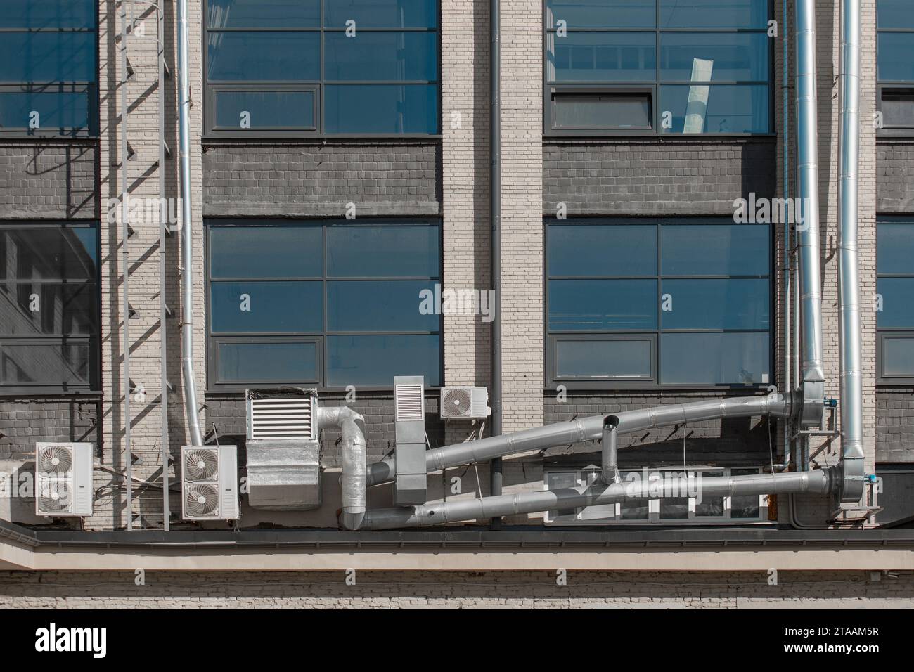 Sistema di tubazioni di ventilazione e aria condizionata esterna sulla facciata di un edificio cittadino. Foto Stock