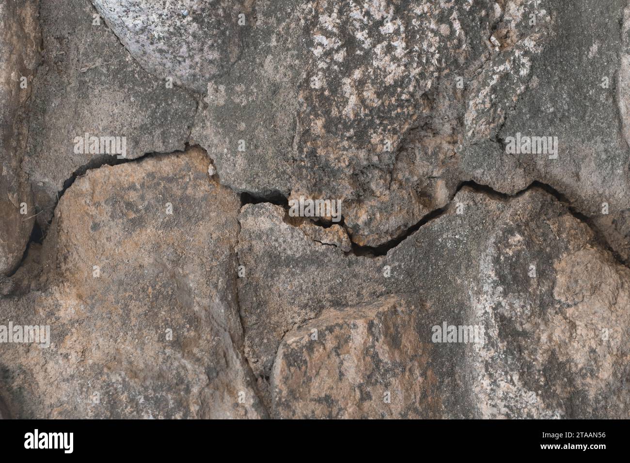 Incrinature sulla vecchia parete in pietra o sulla superficie del pavimento, struttura rotta, primo piano dello sfondo danneggiato. Foto Stock