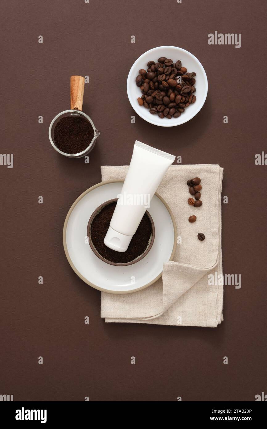Scena minimalista per pubblicità e branding di cosmetici con ingredienti di caffè. Chicchi di caffè e polvere di caffè su oggetti di scena in ceramica decorati con vassoio bianco Foto Stock