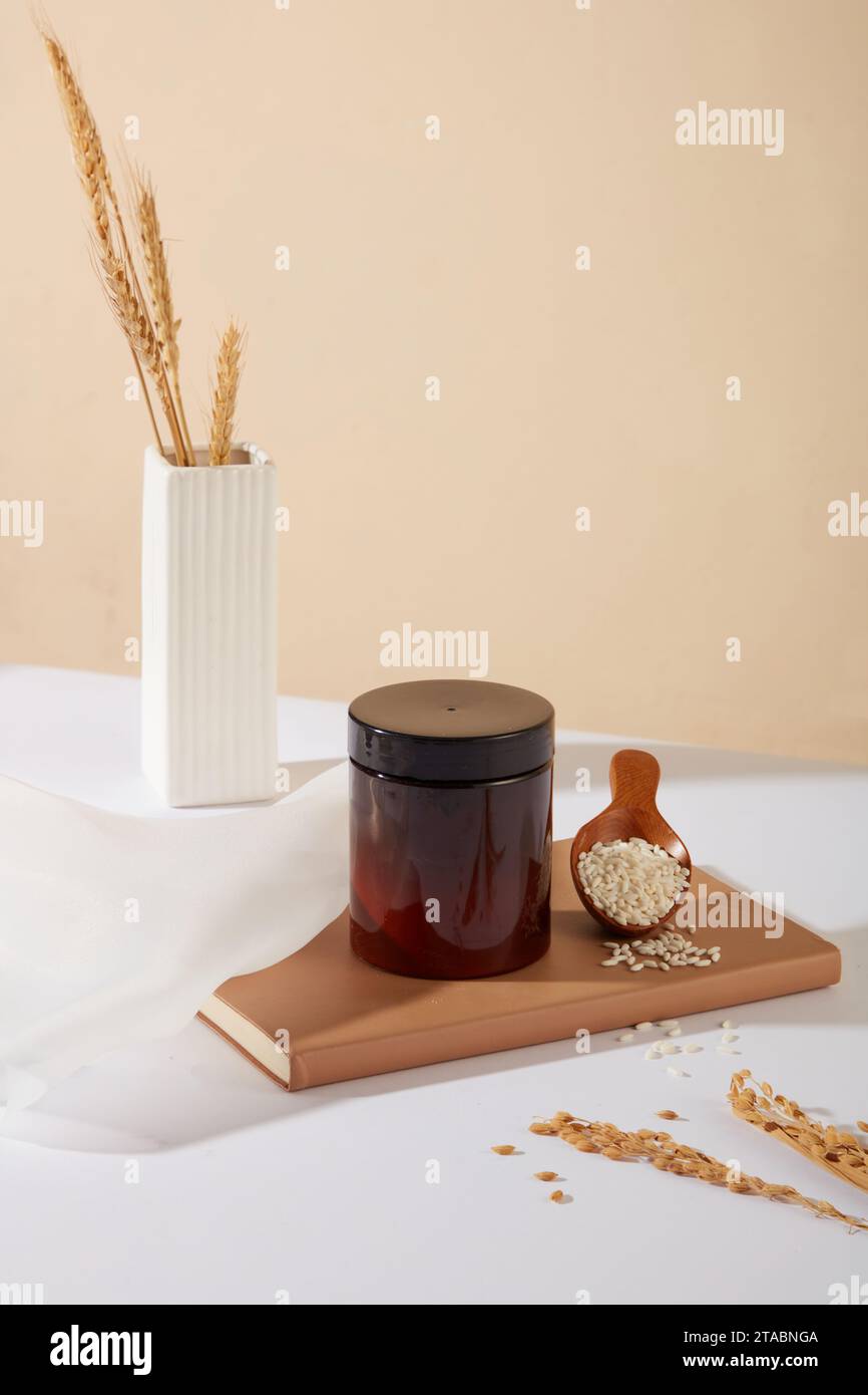 La crusca di riso è un ingrediente naturale spesso utilizzato per esfoliare la pelle. Mockup cosmetico visualizzato su un notebook con un cucchiaio di legno contenente grana intera Foto Stock