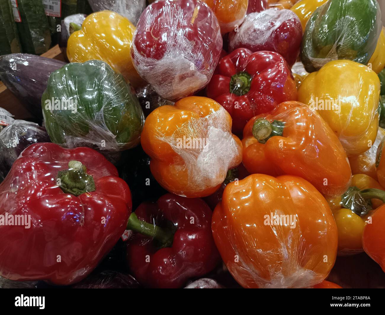 Peperoni verdi, gialli e rossi rivestiti in plastica Foto Stock