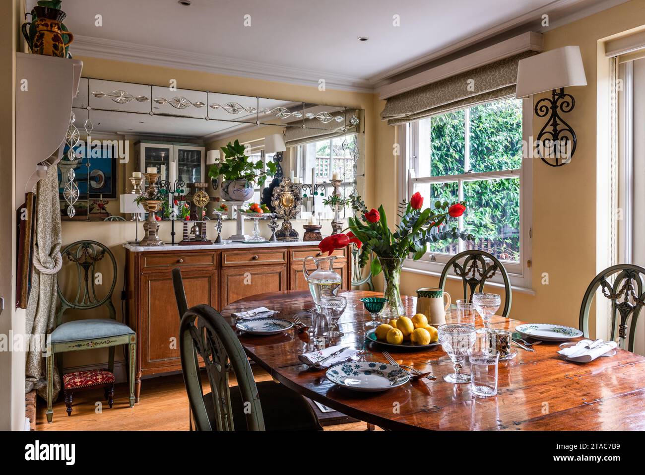Antico tavolo da pranzo e sedie con specchio che aggiunge un senso di spazio alla casa di West London del tardo XIX secolo. Foto Stock
