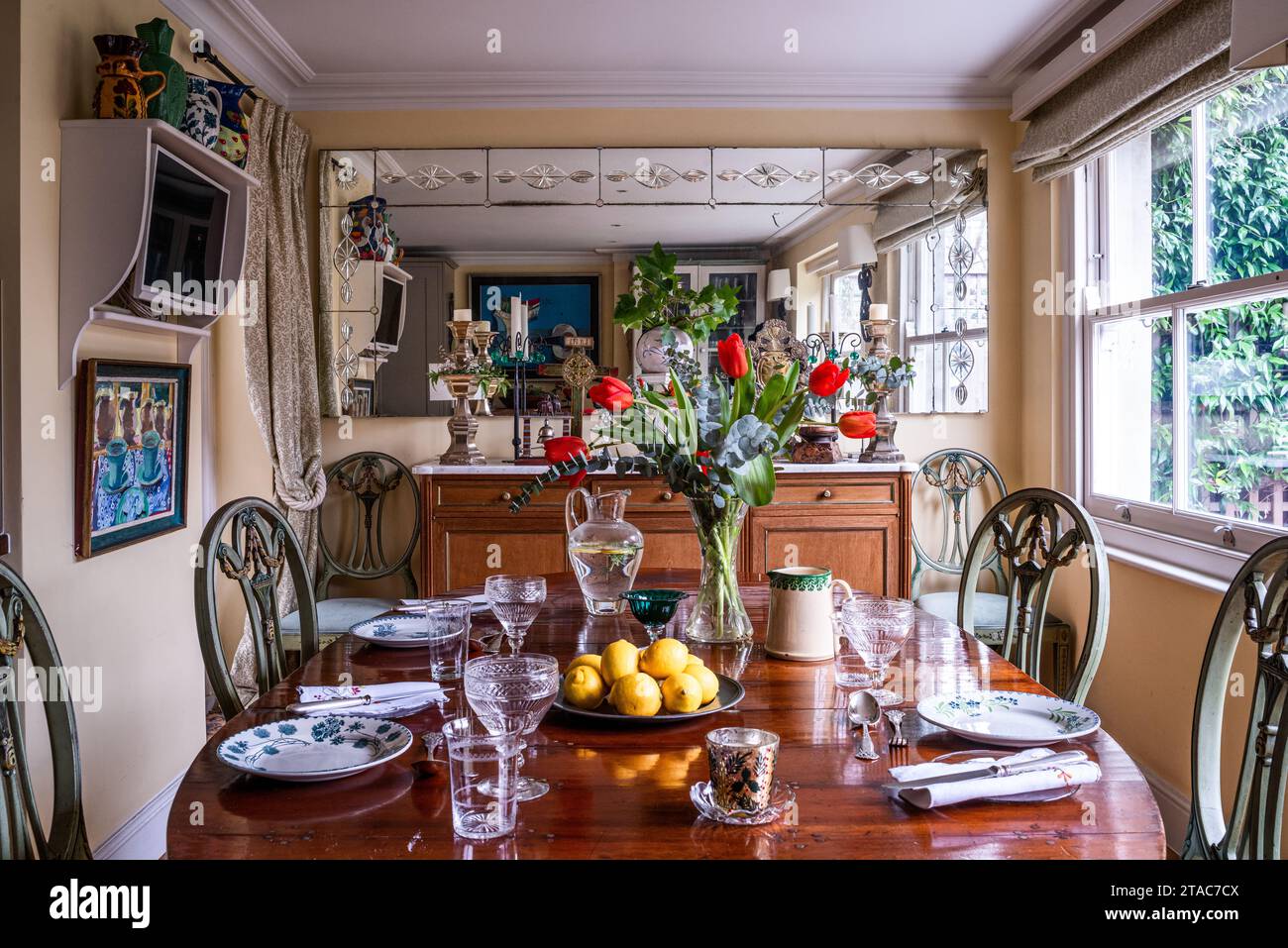 Antico tavolo da pranzo e sedie con specchio che aggiunge un senso di spazio alla casa di West London del tardo XIX secolo. Foto Stock