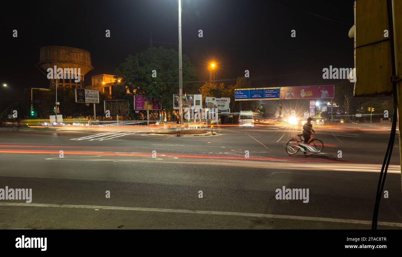 Il traffico stradale cittadino ha una lunga esposizione scattata con sentieri a luce sfocata con l'immagine del segnale di controllo del traffico al mercato sardar ghantaGhar jodhpur raj Foto Stock