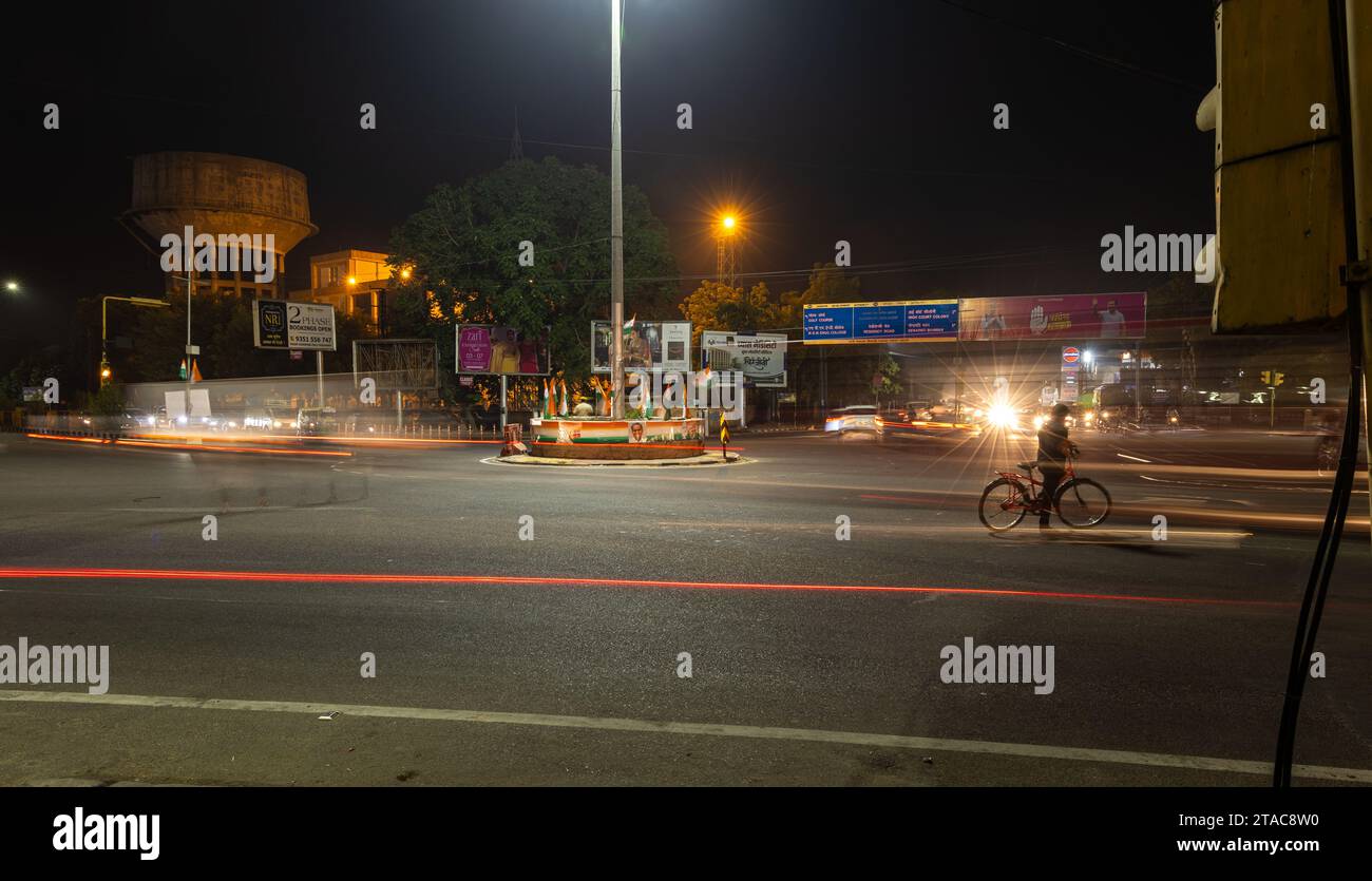 Il traffico stradale cittadino ha una lunga esposizione scattata con sentieri a luce sfocata con l'immagine del segnale di controllo del traffico al mercato sardar ghantaGhar jodhpur raj Foto Stock