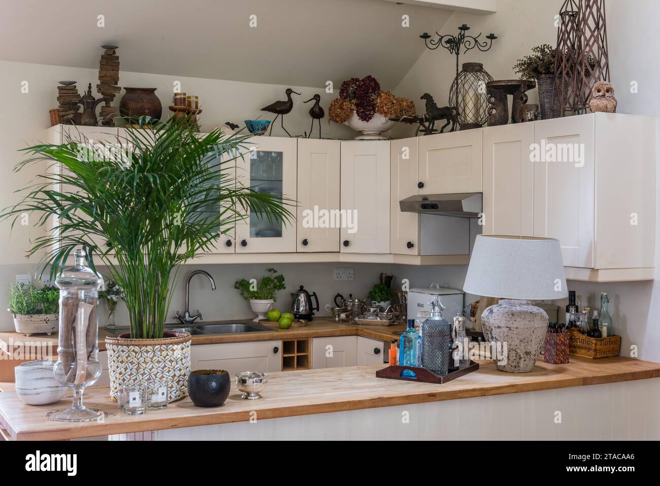 Cucina attrezzata con ornamenti africani scolpiti in stile coloniale a un piano. Truro, Cornovaglia, Regno Unito. Foto Stock