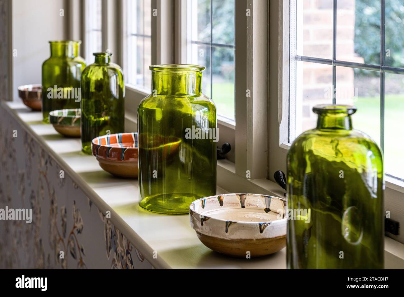 Grandi bottiglie verdi e ciotole in ceramica sul davanzale in stile Arts and Crafts degli anni '1930. Hove, East Sussex, Regno Unito. Foto Stock