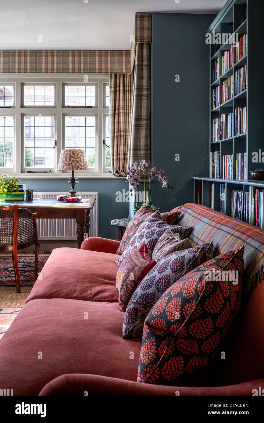 Scrivania alla finestra con divano rosso e scaffali per libri in stile Arts and Crafts degli anni '1930. Hove, East Sussex, Regno Unito. Foto Stock