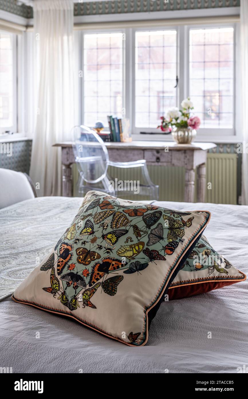 Cuscini con stampa a farfalla Liberty con sedia Louis Ghost al tavolo indiano nella finestra della casa in stile Arts and Crafts degli anni '1930. Hove, East Sussex, Regno Unito. Foto Stock