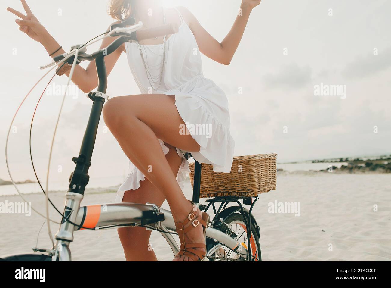 giovane bella donna hipster in abito bianco, vacanze tropicali, stile di tendenza estiva, spiaggia, bicicletta, viaggi, Thailandia, pelle sottile, abbronzata, deposito Foto Stock