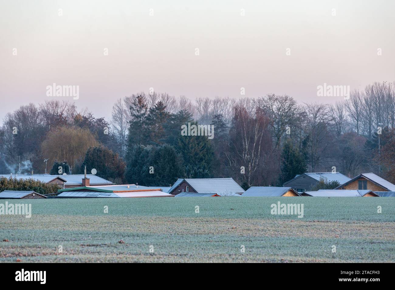 Alcune case in una valle, di cui si possono vedere solo i tetti, sequestrate dal gelo in una mattina d'inverno Foto Stock