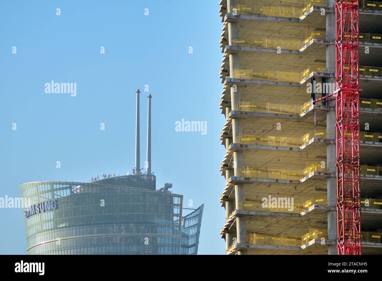 Alto edificio in costruzione. Installazione di pannelli per facciate in vetro su una struttura in cemento armato. Foto Stock