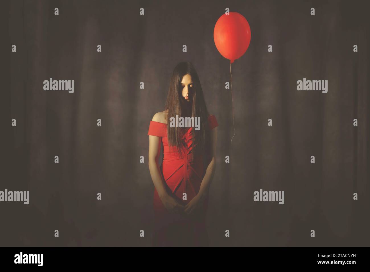 donna surreale vestita elegantemente in rosso con un palloncino rosso che vola accanto a lei Foto Stock