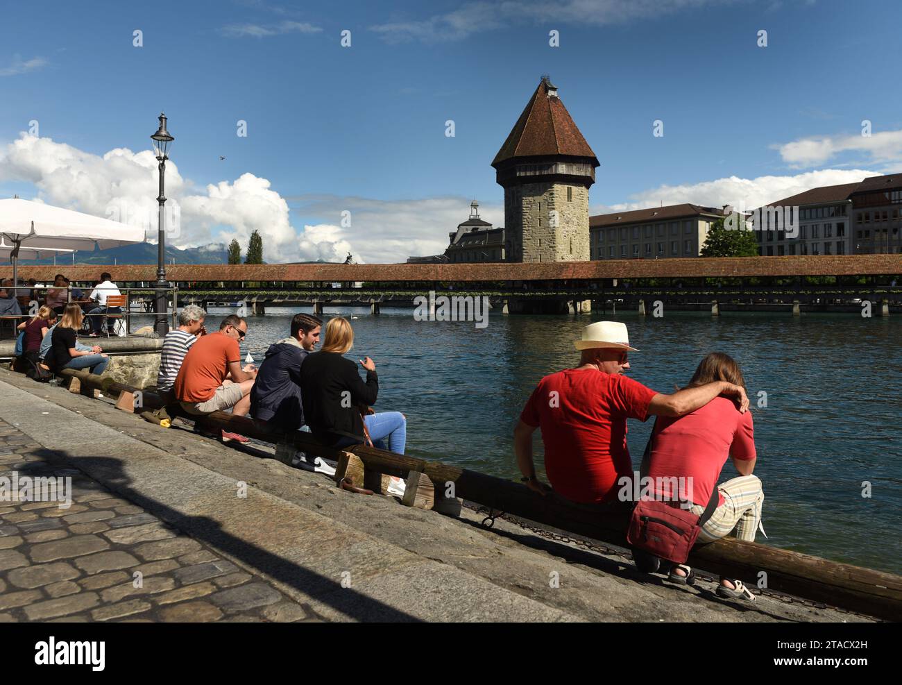 Lucerna, Svizzera - 4 giugno 2017: Le persone siedono sull'argine di Lucerna con il ponte della cappella (Kapellbrucke) e la torre dell'acqua sul lago di Lucerna presso il ba Foto Stock