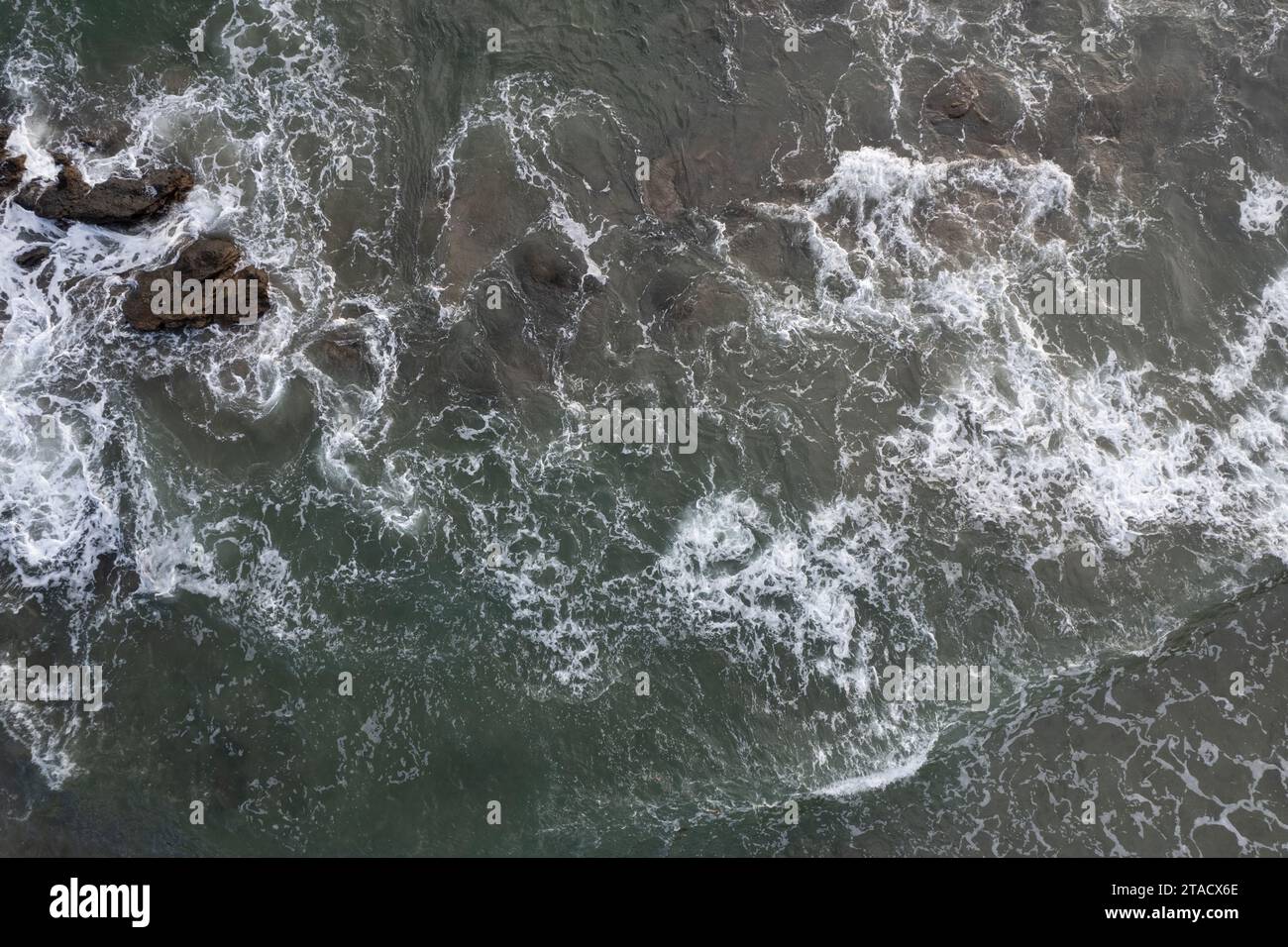 Schiuma nelle onde d'acqua marina dopo il calore delle rocce sopra la vista superiore dei droni Foto Stock