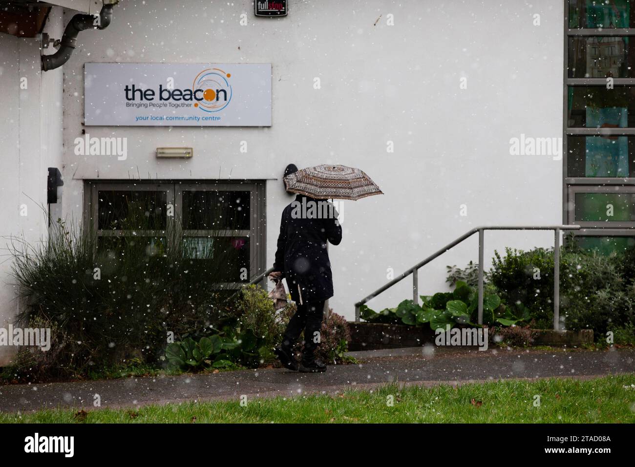 Persona anonima che tiene un ombrello che cammina nella neve verso il Beacon Drop in Centre a Exeter, Devon, Regno Unito Foto Stock