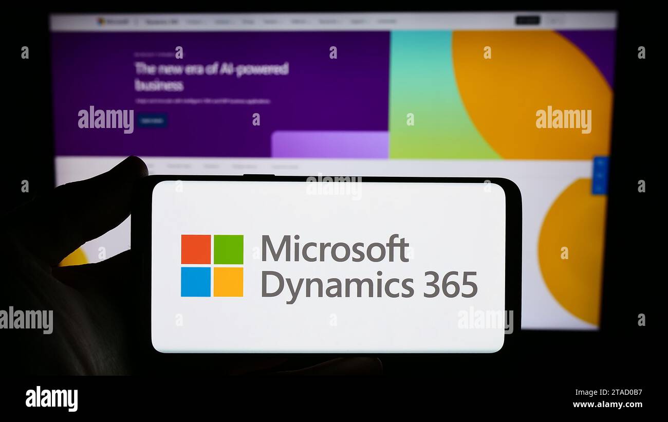 Persona che possiede uno smartphone con il logo del prodotto software di contabilità Microsoft Dynamics 365 davanti al sito Web. Concentrarsi sul display del telefono. Foto Stock