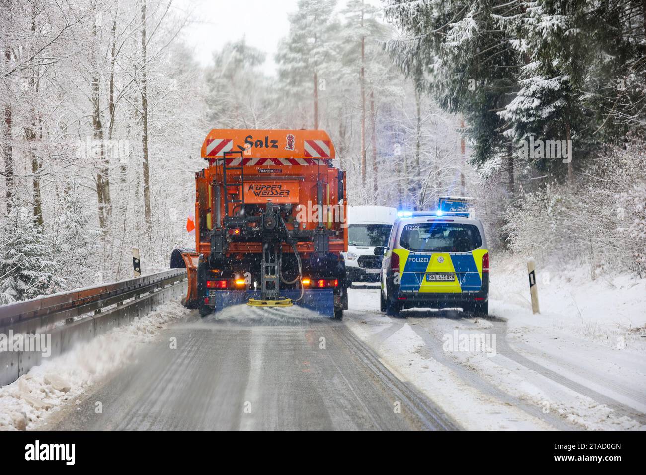 Langenenslingen, Germania. 30 novembre 2023. Un veicolo invernale per l'autorizzazione stradale è in funzione tra Langenenslingen e Friedingen sulla Swabian Alb, mentre un veicolo della polizia protegge diversi camion guasti. Crediti: Thomas Warnack/dpa/Alamy Live News Foto Stock